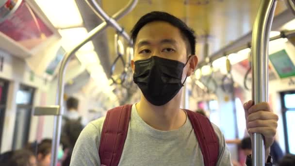 Primo piano di un giovane asiatico che indossa una maschera chirurgica nera nel treno della metropolitana durante il nuovo tipo Coronavirus Covid-19 focolaio di polmonite e pm 2,5 smog crisi di inquinamento atmosferico nella grande città — Video Stock