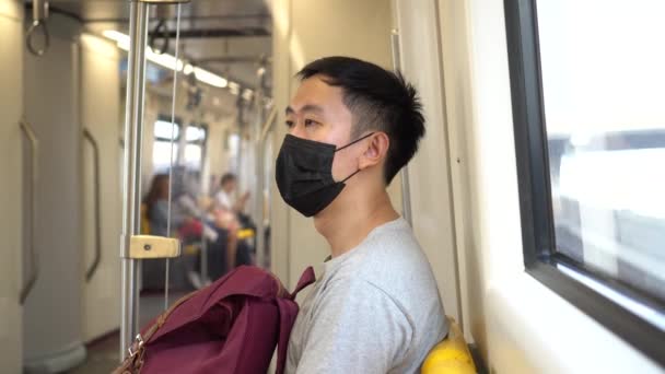 新しいタイプの間の地下鉄の列車で黒い外科用フェイスマスクを身に着けている1人の若いアジア人男性のクローズアップコロナウイルスCovid-19肺炎発生 — ストック動画