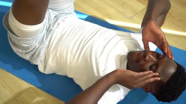 Joven hombre afroamericano haciendo ejercicio de sentada en la esterilla de yoga en el gimnasio. Modelo de fitness masculino que realiza crunch en el gimnasio — Vídeo de stock