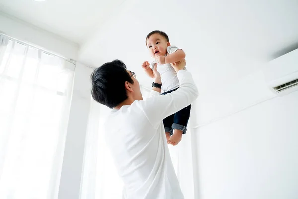 Asijský otec zvedá svého malého vlastního syna létat ve vzduchu — Stock fotografie