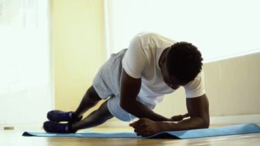 Spor salonunda mat yan tahta egzersiz yaparken atletik Afro-Amerikan adam bir kol üzerinde dengeleme
