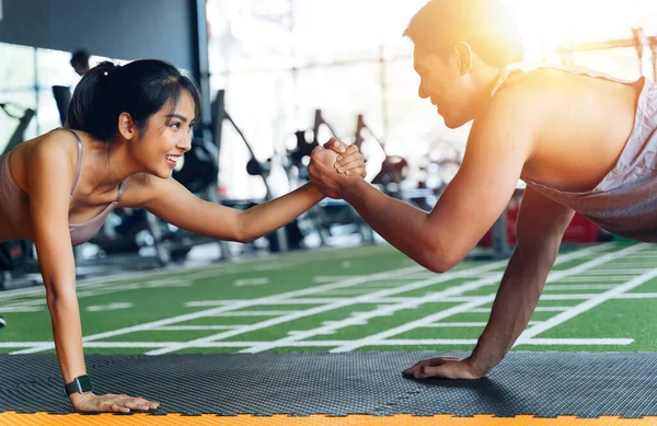 Saludable pareja sonriente de hombre y mujer dando chocar los cinco mientras empujan hacia arriba en el gimnasio de fitness. Asiáticos deportistas haciendo ejercicio juntos — Foto de Stock