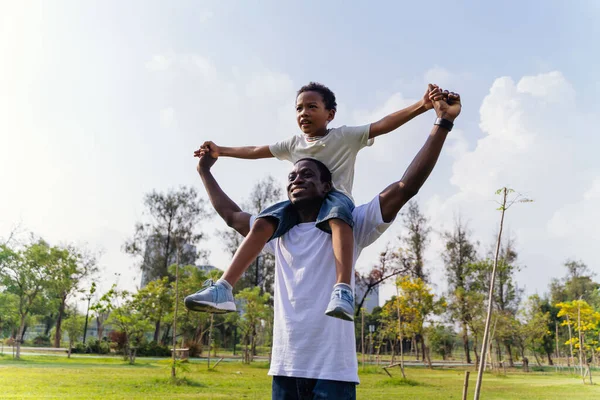 Açık hava parkında mutlu Afrika kökenli Amerikalı baba ve oğul. Aile hafta sonu etkinliği — Stok fotoğraf