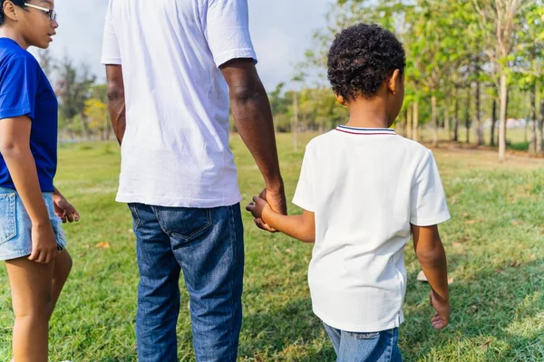 African American father walking in the nature with pre-teen daughter and holding hands with son. Recreational family gathering on weekend — Stok fotoğraf