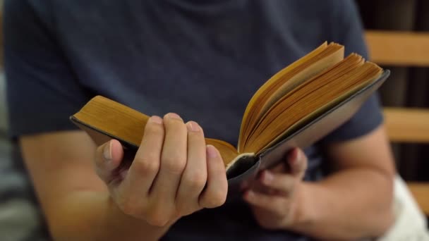 Primo piano di uomo sereno in abbigliamento casual trascorrere il tempo libero a leggere un libro all'interno di casa a letto. Tempo libero e tempo libero — Video Stock