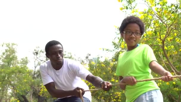 Афроамериканский отец и дочь тянут веревку вместе в перетягивании каната военного соревнования - семья на досуге в выходные — стоковое видео