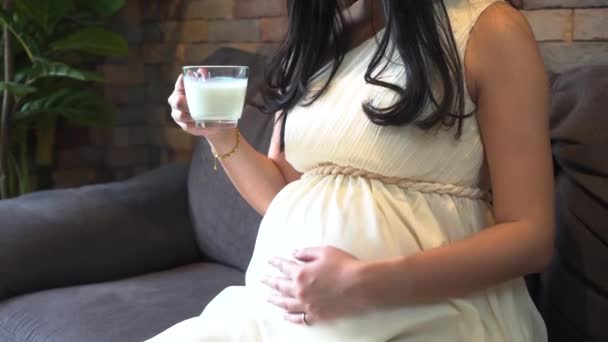 Беременная женщина пьет молоко дома — стоковое видео