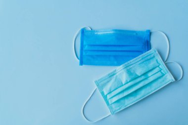 Mavi arka planda tıbbi koruyucu maskeler ve kopyalama alanı. Coronavirus Covid-19 salgınına karşı korunmak için tek kullanımlık yüz maskeleri. Sağlık hizmeti tıbbi cerrahi konsepti