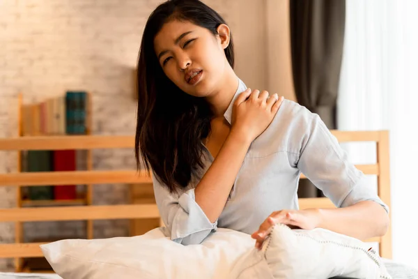 Portrait of 20s young Asian woman having pain in her neck and back in bedroom at night. Cervical arthritis, osteochondrosis, diseases of musculoskeletal system — Stock Photo, Image