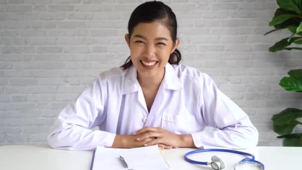 Просмотр видео-чата с азиатской женщиной-врачом и пациенткой при обсуждении и диагностике на ноутбуке и при взгляде в камеру — стоковое видео