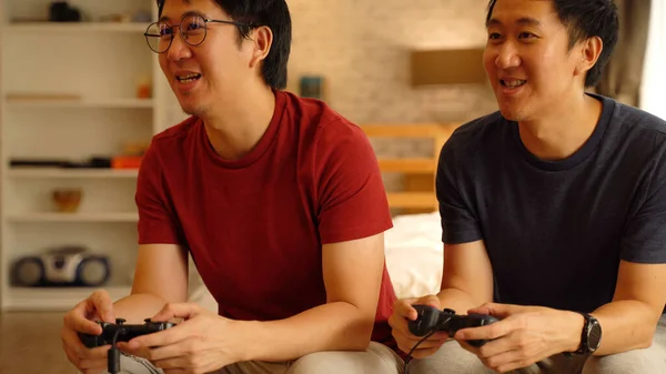 Jonge mannelijke vrienden die thuis met joystick spelen. aziatische mannen kijken tv naar videogame samen spelen — Stockfoto
