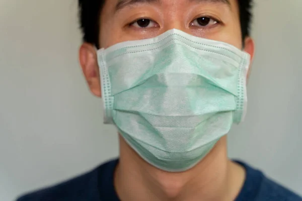 Portret close-up van een Aziatische man met een beschermend gezichtsmasker tegen besmettelijke ziekte en coronavirus. — Stockfoto