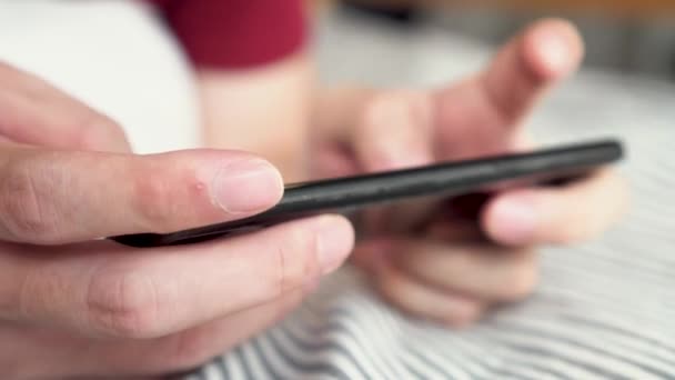 Las manos cerca jugando un juego móvil en el teléfono inteligente en casa. Joven jugador usando el teléfono móvil para el juego en línea — Vídeo de stock