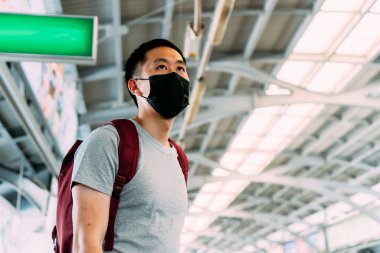 Coronavirus Covid-19 pnömoni salgını ve 2.5 numaralı hava kirliliği krizi sırasında siyah cerrahi maske takmış genç bir Asyalı 'yı yakından takip edin.