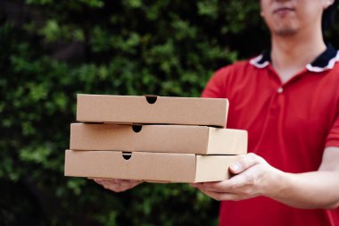 Pizza teslimatçısı çocuk elinde pizza kutularıyla kapının önünde fotokopi alanı ile bekliyor.