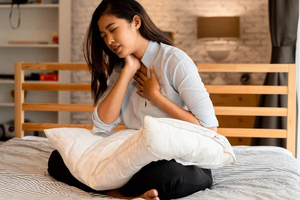 Geceleri yatak odasında nefes almakta zorlanan 20 'li yaşlardaki Asyalı genç bir kadının portresi. Nefes darlığı, astım, nefes almakta zorlanıyorum.