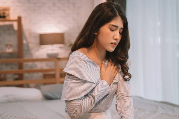 Geceleri yatak odasında nefes almakta zorlanan 20 'li yaşlardaki Asyalı genç bir kadının portresi. Nefes darlığı, astım, nefes almakta zorlanıyorum.