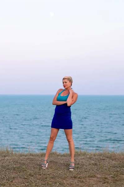 The woman in a blue dress against the background of the sea — Stock Photo, Image