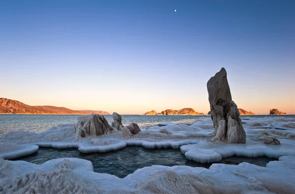 Na wybrzeżu zimą zimne morze o zachodzie słońca. — Zdjęcie stockowe