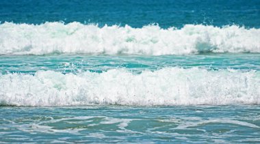 Turkuaz yeşil dalgaları Endonezya kumlu bir plaj üzerinde köpük ile