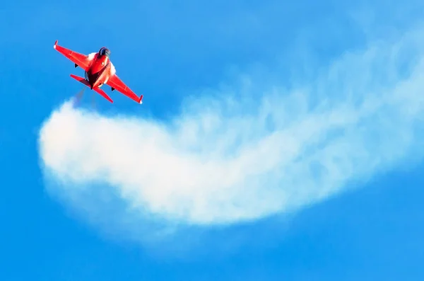 Jet de chasse rouge dans le ciel bleu avec traînée de fumée blanche — Photo