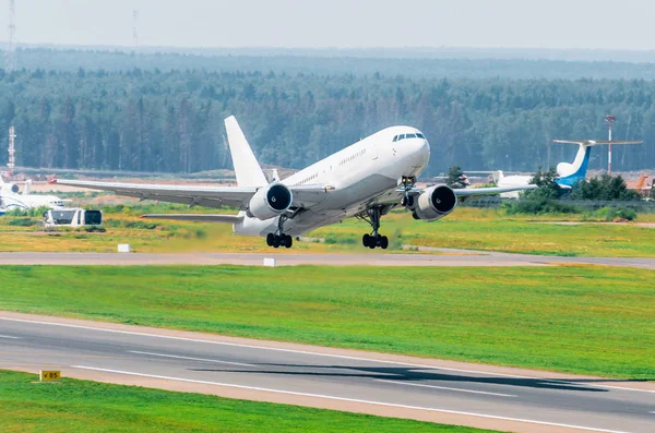 Avión blanco grande despegue en el aeropuerto en una vista superior en la pista, bosque lejano —  Fotos de Stock