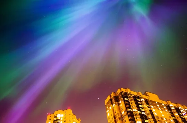 Aurora borealis starry night over the city and houses.