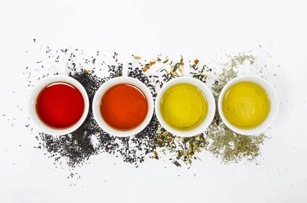 Coleção de chás diferentes em copos com folhas de chá em um fundo branco — Fotografia de Stock