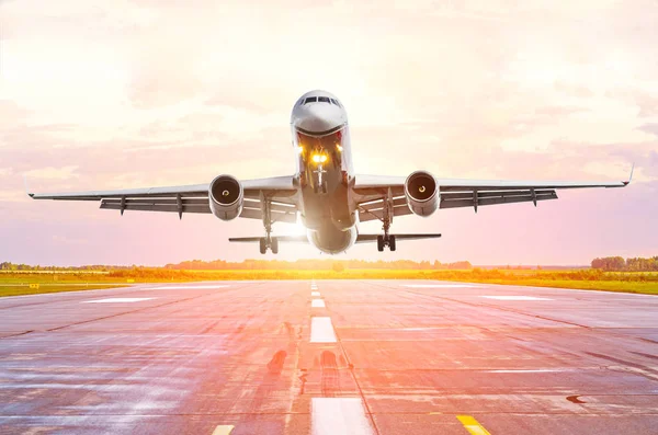 El avión sube, vuela aterrizando en la pista en el aeropuerto amanecer puesta de sol — Foto de Stock