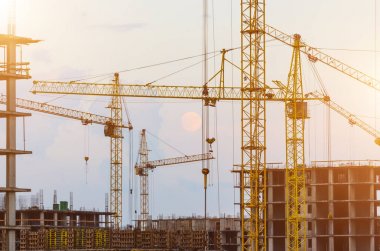 Endüstriyel vinçler ve güneş doğarken siluetler inşa etmek