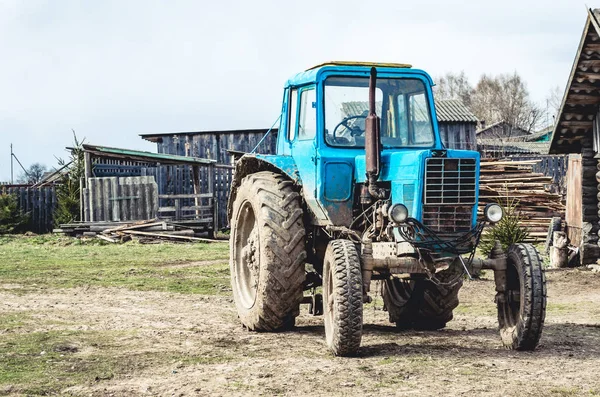 Una vieja vista frontal del tractor en el campo entre graneros y cobertizos . —  Fotos de Stock