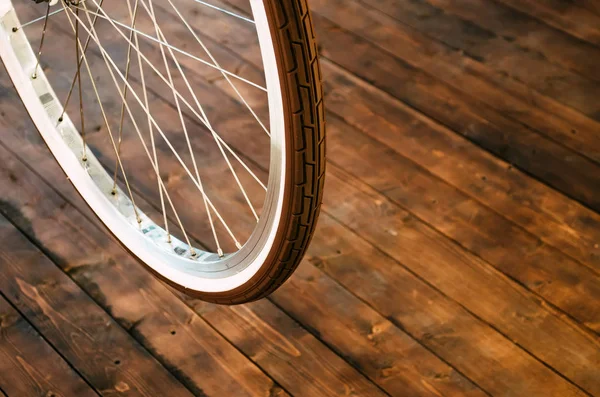 Rad eines stylischen Fahrrades mit weißer Felge und braunem Gummireifen auf stylischem Holzhintergrund. — Stockfoto