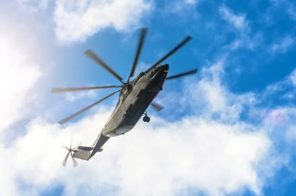 A large transport helicopter is gaining height in the sky clouds of sun, breakdown of steam at the ends of the blades of the propeller. — Stock Photo, Image