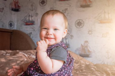 Bir yaşındaki bebek şakacı güler ve elini çenesine için tutar.