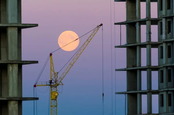 Gebouw op de achtergrond een kraan en lucht met een volle-maan avond. — Stockfoto