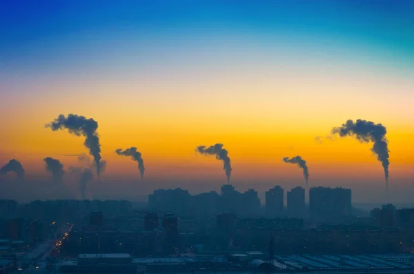 Esti kilátás a város füst kibocsátása kémények napnyugtakor ipari táj — Stock Fotó