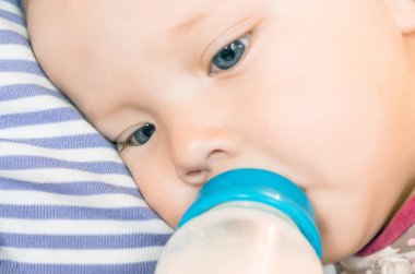 Beslenme, Bebek el ile bir şişe süt tutuyor. Yakın çekim