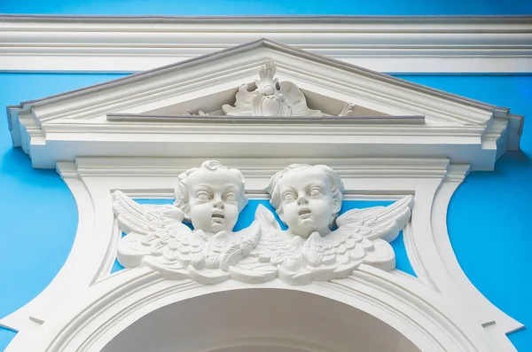 Los rostros de los ángeles sobre la ventana de estuco en la pared de la iglesia — Foto de Stock
