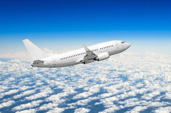 White airplane flies high in the sky above the clouds blue sky Stock Image