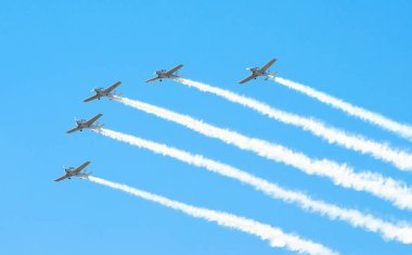 Beyaz turboprop uçak grup beyaz bir mavi gökyüzü karşı duman izi ile