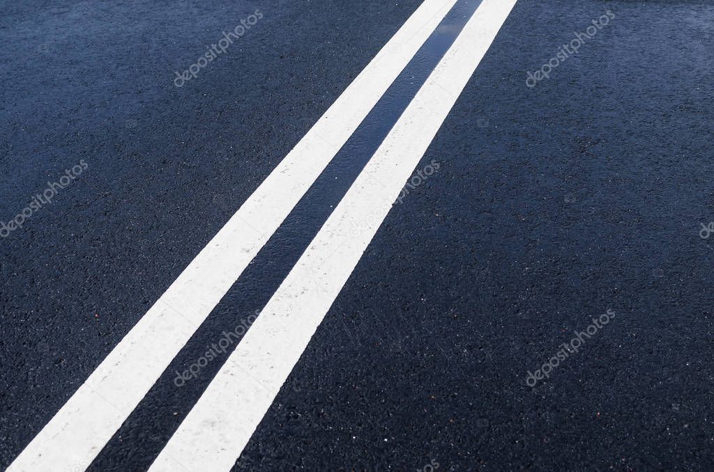 Double solid white line on wet asphalt