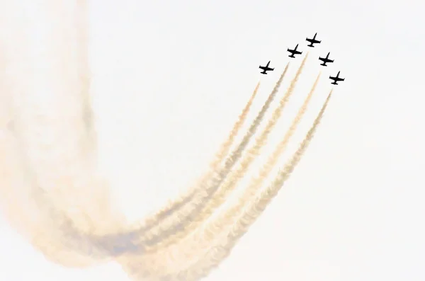 Ομάδα λευκό μαχητικό αεροπλάνο με ένα ίχνος από λευκό καπνό κατά ένα γαλάζιο ουρανό — Φωτογραφία Αρχείου