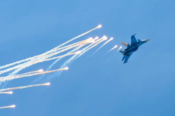 Μαχητικό αεροσκάφος πετά και πυροβολεί πιστόλια θερμού αέρα στο μπλε του ουρανού... — Φωτογραφία Αρχείου