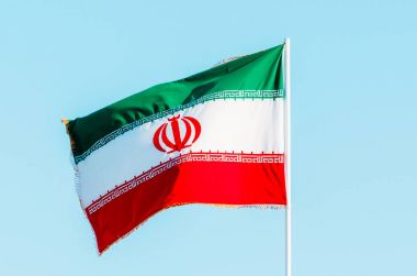 Mavi gökyüzünde renkli Iran bayrağı sallayarak