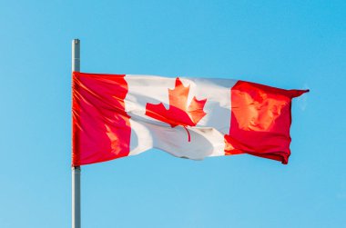 Mavi gökyüzünde renkli Kanada bayrağı sallayarak
