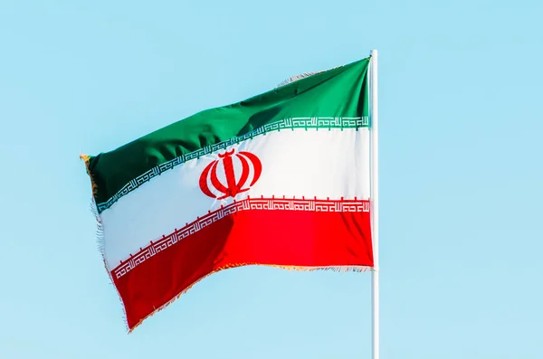 Vilkuttaa värikästä Iranin lippua sinisellä taivaalla — kuvapankkivalokuva