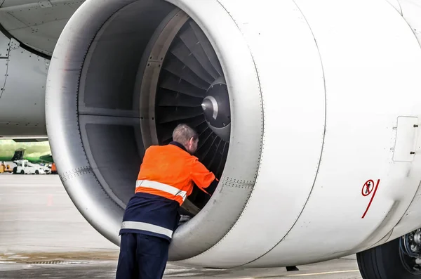 Mänskliga tekniker kontrollerar motorns turbin flygplan bladet efter voyage och psodki i parkering på flygplatsen — Stockfoto