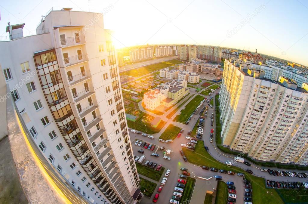 View from the height of the balcony to the sunset and the courtyard of the city landscape with cars and parking
