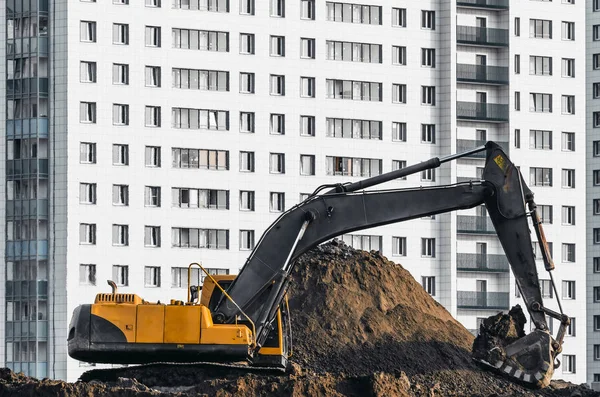 Trabajos de excavadora en el suelo sobre fondo de casas de varios pisos — Foto de Stock