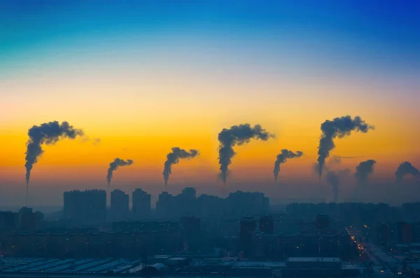 Вечерний вид на промышленный ландшафт города с выбросами дыма из труб на закате — стоковое фото